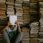 Man reading a book in front of a stack of books | Best Self-Help Books for Men