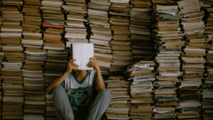 Man reading a book in front of a stack of books | Best Self-Help Books for Men