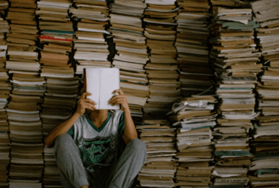 Man reading a book in front of a stack of books | Best Self-Help Books for Men