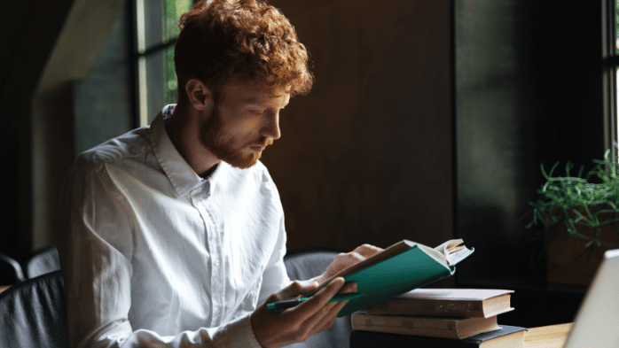 Young man reading books and taking notes | How to Self-Improve As A Man