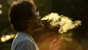 man blowing smoke trying to escape from life