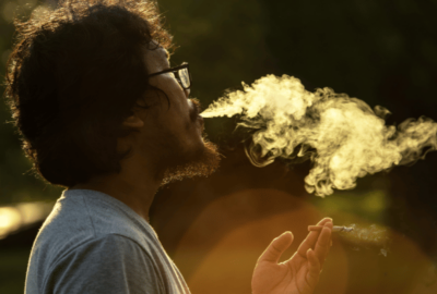 man blowing smoke trying to escape from life